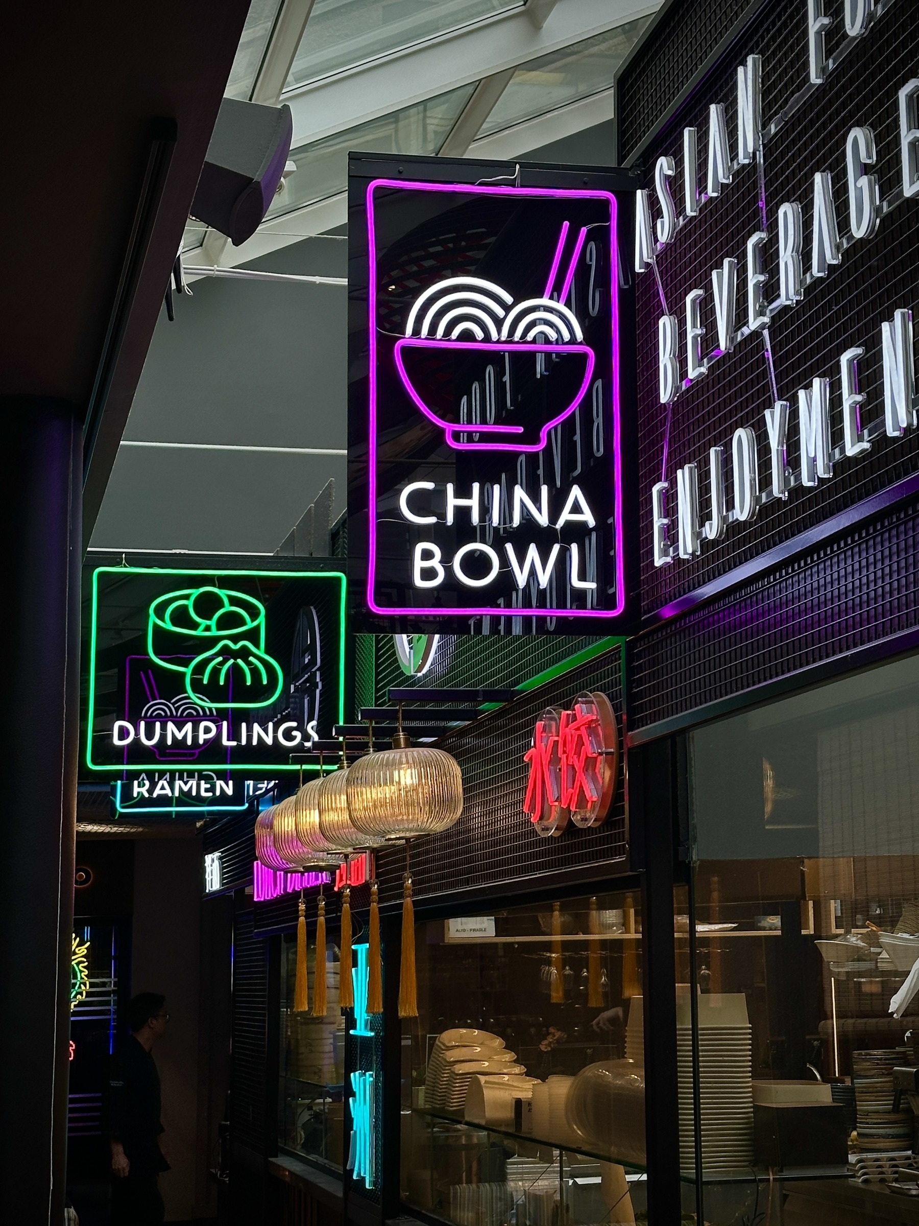 Upprätad vy med neonskyltar och asiatiska matstationer på Eat Market